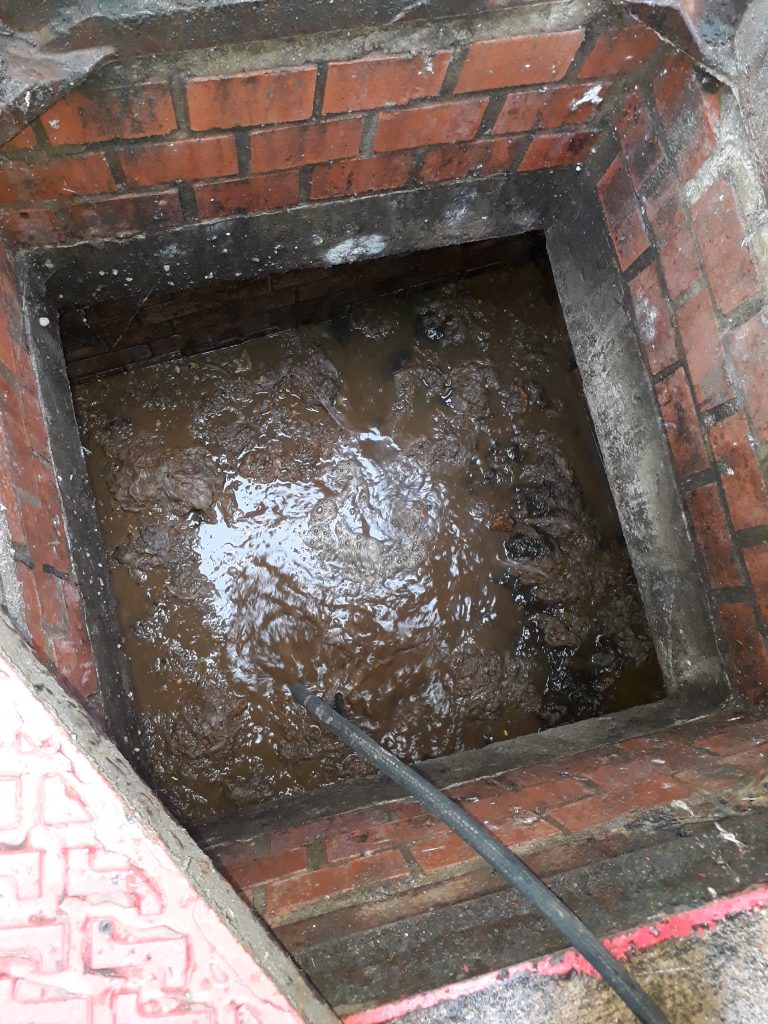 Blocked manhole to be unblocked by drain rod and jetting